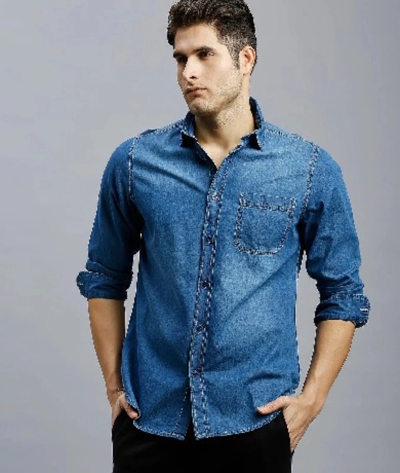Kolları kıvrık orta mavi denim gömlek giyen erkek