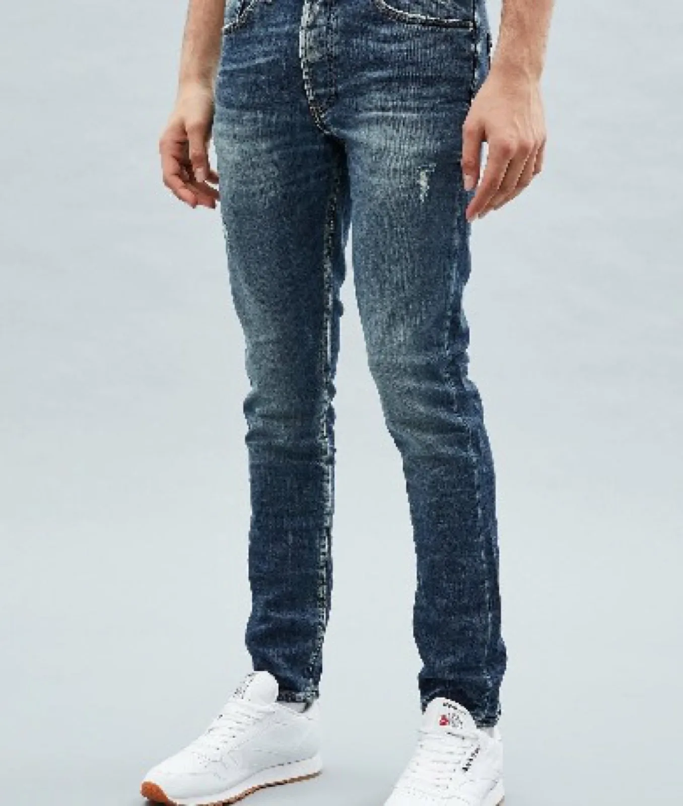 Orta yıkama slim fit kot pantolon ve beyaz spor ayakkabı giyen erkek